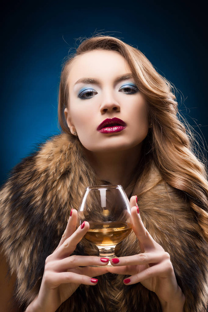 Beautiful girl in a fur raccoon collar holds in hands a glass of - Foto, Imagem
