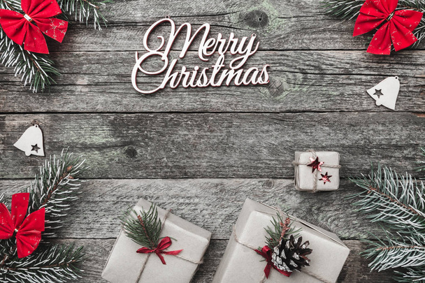 Upper, top, view from above of white winter figurines, evergreen branch, red toys, presents and Merry Christmas inscription on gray background, with space for text writing, greeting - Fotoğraf, Görsel