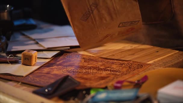 Homem está embalando lembrança artesanal em papel de embrulho em uma pequena oficina aconchegante
 - Filmagem, Vídeo