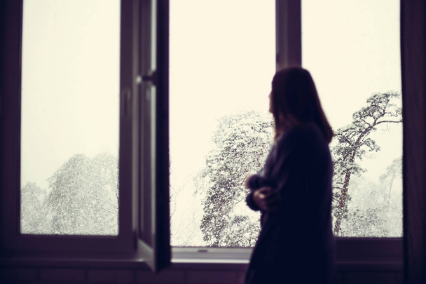 少女は窓際に立っているし、雪が降ってどのように見て - 写真・画像