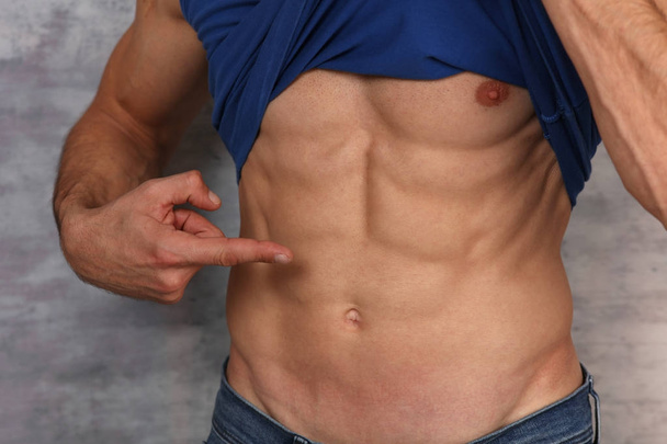 Sportmann zeigt auf perfekte Bauchmuskeln. Sixpack Trainingsergebnisse - Foto, Bild