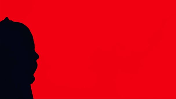 Силуэт человека в черном капюшоне, красный фон. Портрет человека-невидимки в капюшоне с красным занавесом
 - Фото, изображение