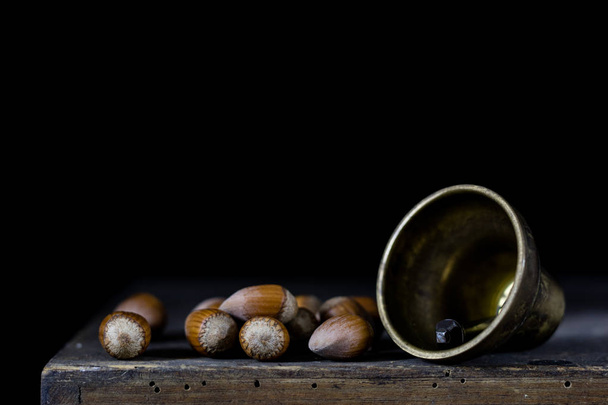 Nüsse in einem natürlichen Beutel. eine Tüte Nüsse und eine Glocke an einem alten dunklen W - Foto, Bild