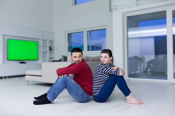 young couple sitting with back to each other on floor - Valokuva, kuva
