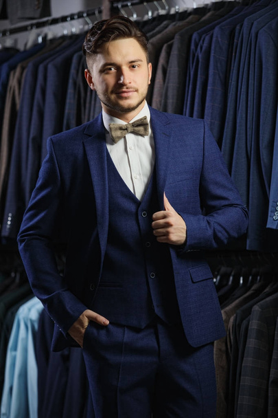 Handsome caucasian businessman dressed in the suit. In the background classic suits and jackets - Foto, Imagem