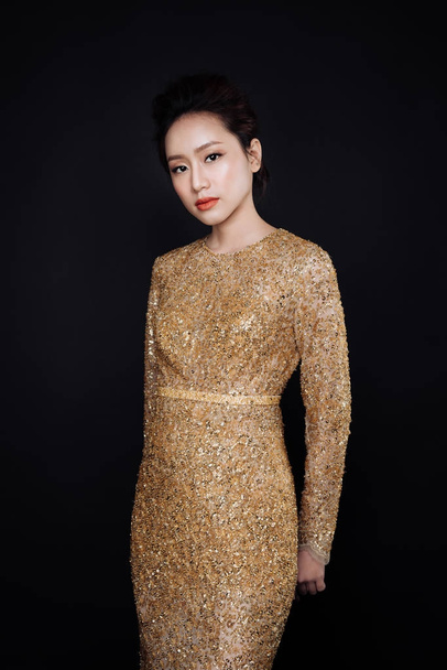 Portret piękne sexy asian kobieta sobie złoty błyszczący strój na czarnym tle. - Zdjęcie, obraz