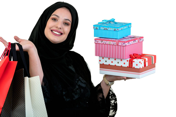 Happy young muslim woman with shopping bag and gift boxes isolated over white background - Fotó, kép