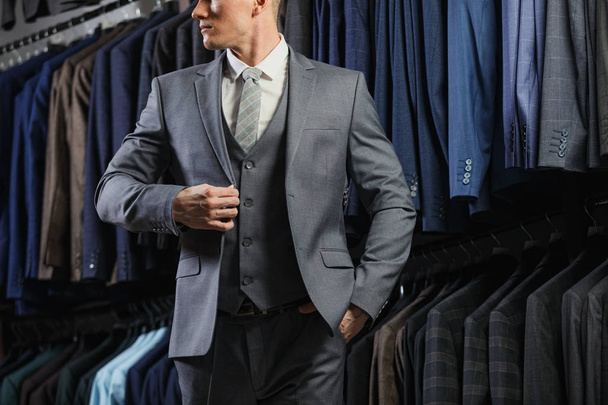 Handsome caucasian businessman dressed in the suit. In the background classic suits and jackets - Foto, imagen