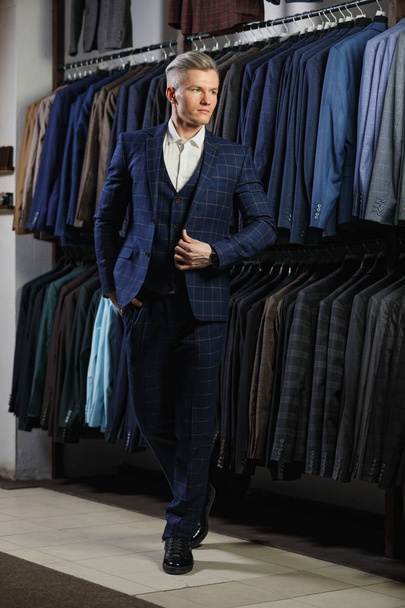 client is elegant guy in jacket. In the background classic suits and jackets - Foto, Imagen