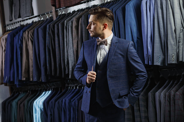Handsome businessman in classic suit. A young stylish man in a jacket. It is in the showroom, trying on clothes, posing. Advertising photo - Photo, Image