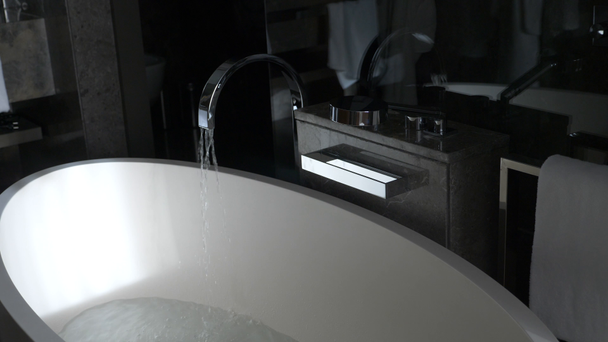Sterke waterdruk die voortvloeien uit een stijlvolle, verchroomde kraan in een stijlvolle, mooie bad. 4 k timelapse - Video