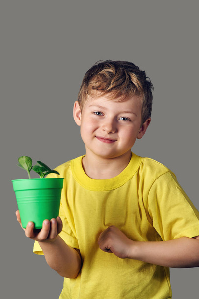 Hymyilevä poika versot kädessä, harmaalla pohjalla
 - Valokuva, kuva