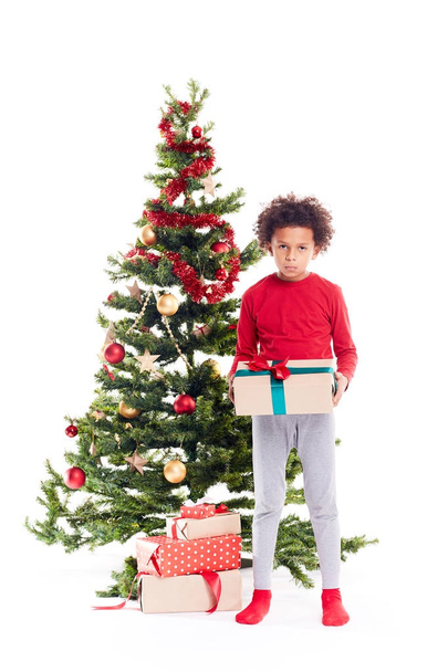 Mixed race boy near Christmas tree - 写真・画像