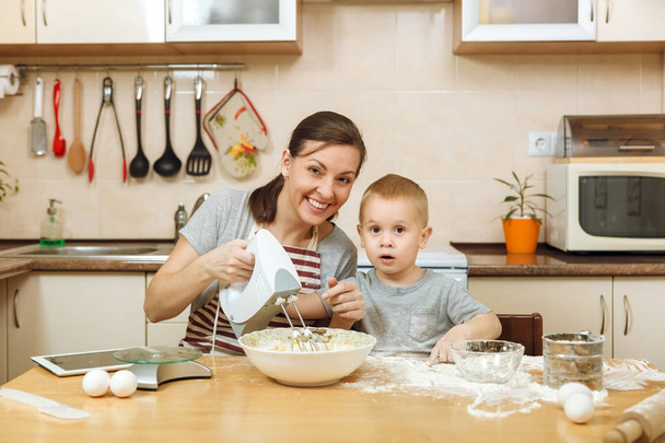 Kis gyerek fiú anyja főzni a karácsonyi gyömbéres keksz könnyű konyhában az asztalra tabletta segít. Boldog család anya 30-35 éves és a hétvégén reggel otthon 2-3 gyerek. Kapcsolat fogalma - Fotó, kép