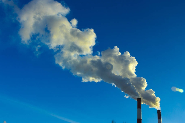 The pipe of the plant emits harmful substances into the atmosphere. Close-up on a sky background - Photo, Image