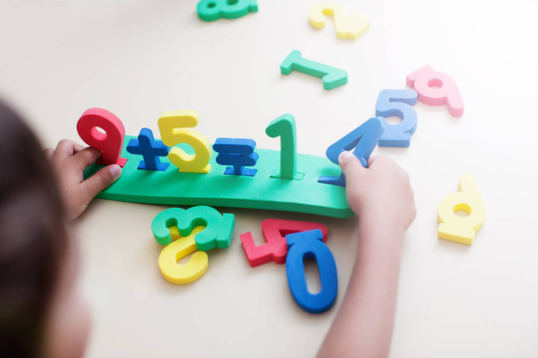 Closeup shot of child boy hands playing with colorful numbers over white table background - Photo, Image