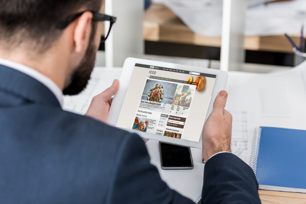 businessman holding tablet with loaded bbc food page - Foto, Bild
