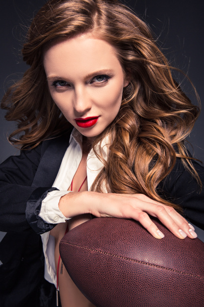 πορτρέτο του ελκυστική γυναίκα κρατώντας αμερικανικό ποδόσφαιρο μπάλα απομονώνονται σε γκρι - Φωτογραφία, εικόνα