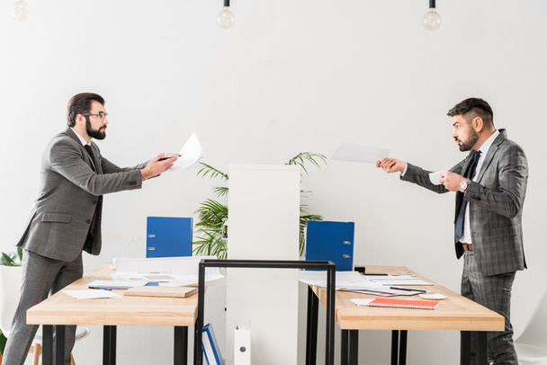 hommes d'affaires se querellant dans le bureau et montrant des documents les uns les autres
 - Photo, image
