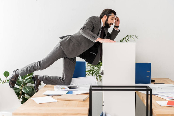 бизнесмен шпионит за коллегой таблицей выше раздела в офисе
 - Фото, изображение