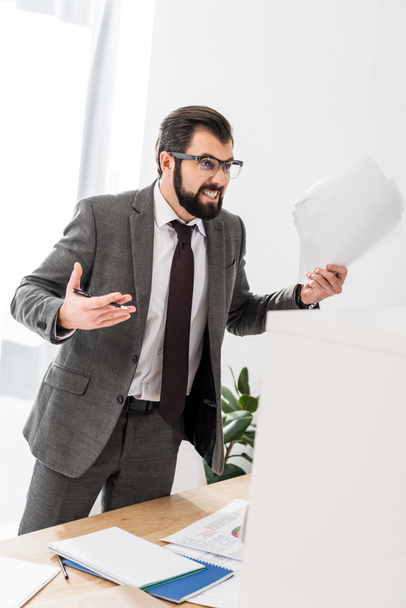 irritated businessman holding documents and screaming at someone - 写真・画像