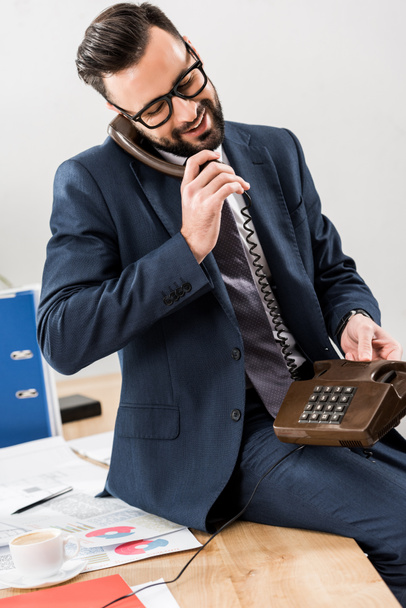 sonriente hombre de negocios hablando por teléfono fijo en la oficina
 - Foto, Imagen