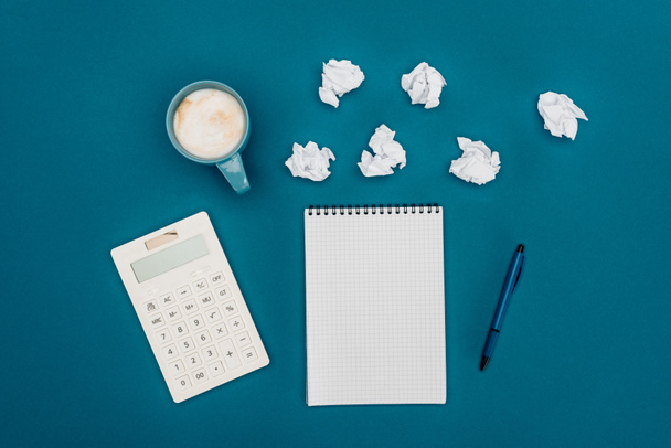 top view of blank notebook with pen, calculator and crumpled papers on blue - Foto, immagini