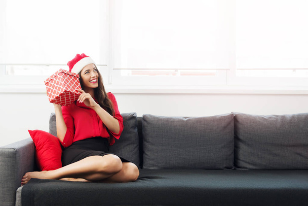 Beautiful businesswoman with Santas hat holding a present - Photo, image