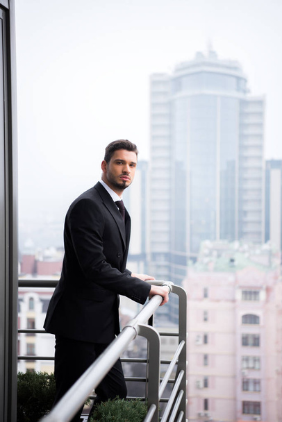 portrait of young pensive man in suit standing at restaurant balcony - Fotografie, Obrázek