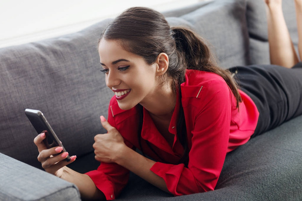 Beautiful young businesswoman using a cellphone on a sofa - Фото, изображение
