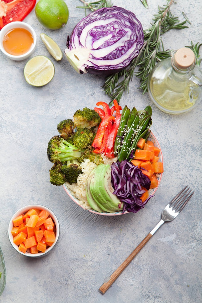 Tasty healthy bowl for lunch with couscous, baked broccoli and carrots cut in cubes, fried peas, avocados and red cabbage. Easy vegetarian diet concept. Rustic background. Top view. - Φωτογραφία, εικόνα
