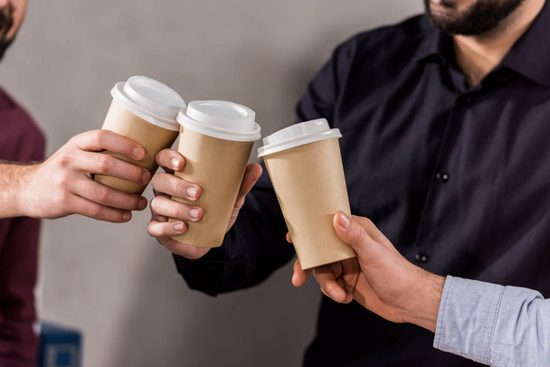 imagen recortada de los hombres de negocios tintineo con tazas de café desechables
  - Foto, imagen