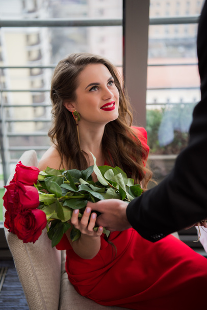 Teilansicht des Mannes präsentiert Blumenstrauß für Freundin bei romantischem Date im Restaurant, Valentinstag - Foto, Bild