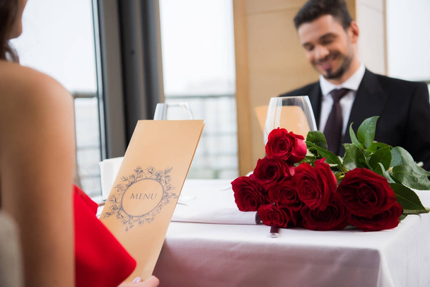 selective focus of couple reading menu on romantic date in restaurant on st valentine day - Fotó, kép