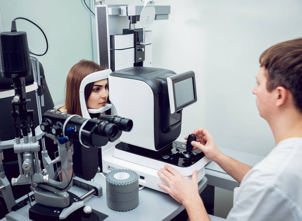 Young woman checking her vision with ophthalmologist. Medical equipment. - Фото, изображение