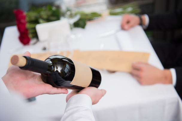 Garson gösteren şişe şarap Restoran masada ziyaretçi için seçici odak - Fotoğraf, Görsel