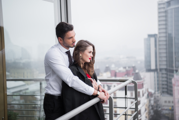 молодая влюбленная пара, стоящая на балконе вместе
 - Фото, изображение