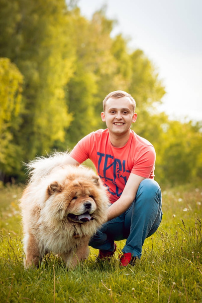 Young man with his dog chow-chow walking in the park and having good time - Foto, afbeelding