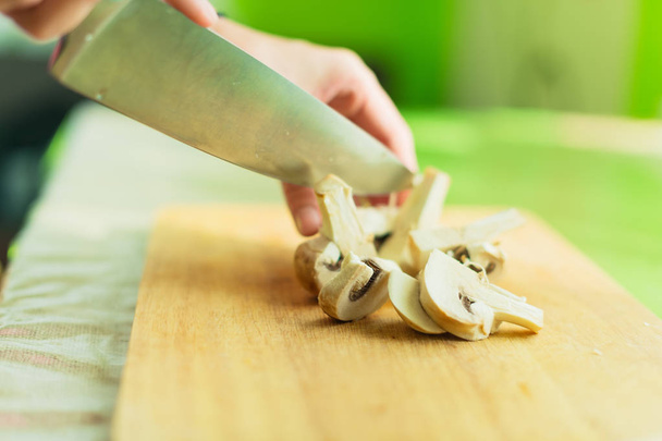 Female hands cut into large wooden mushrooms on a cutting board. - Photo, image