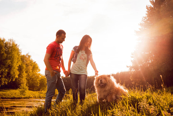 Young couple with their dog chow-chow walking in the park and having good time - Foto, immagini