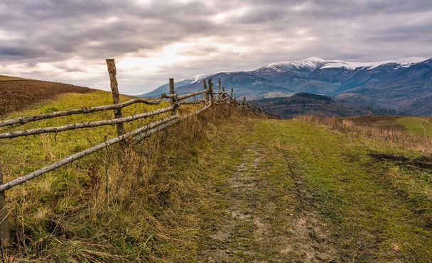 fence along dirt road in mountainous rural area - Zdjęcie, obraz