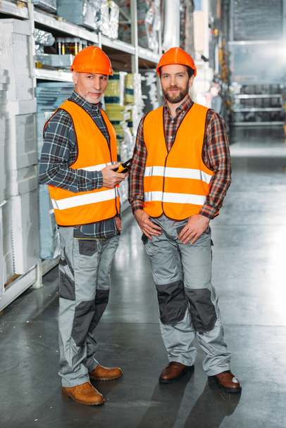 dos trabajadores masculinos sosteniendo walkie talkie en stock de envío
 - Foto, Imagen