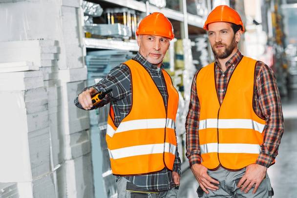 two male workers holding walkie talkie in storehouse - Photo, Image
