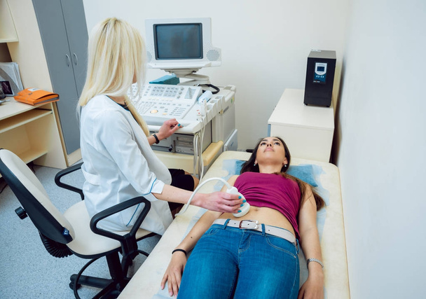 Female caucasian doctor and femele middle eastern patient. Ultrasound equipment. Diagnostics. Sonography. - Φωτογραφία, εικόνα