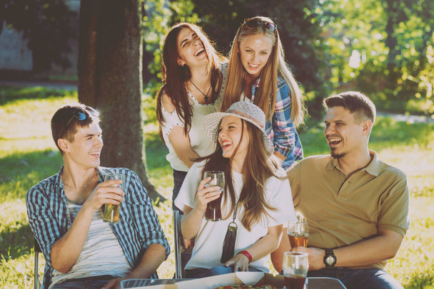 Cheerful friends on picnic in the park. Smiling and talking. - 写真・画像