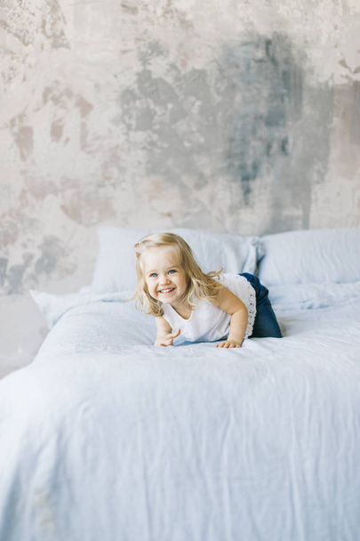 beautiful little blonde girl smile in bed at home - Fotó, kép