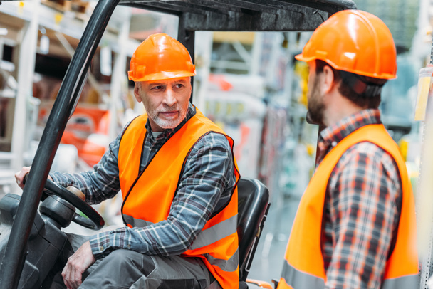 worker and his senior colleague working with forklift machine in shipping stock - Photo, Image