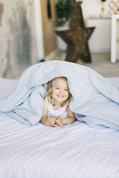 cute little blonde girl smile in bed at home - Fotó, kép