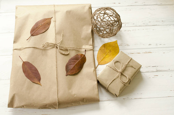 Gifts packaged in craft paper and  dry autumn leaves - Foto, afbeelding