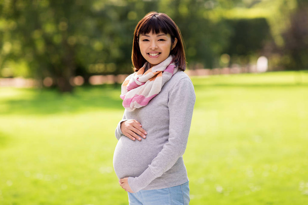 happy pregnant asian woman at park - Foto, afbeelding